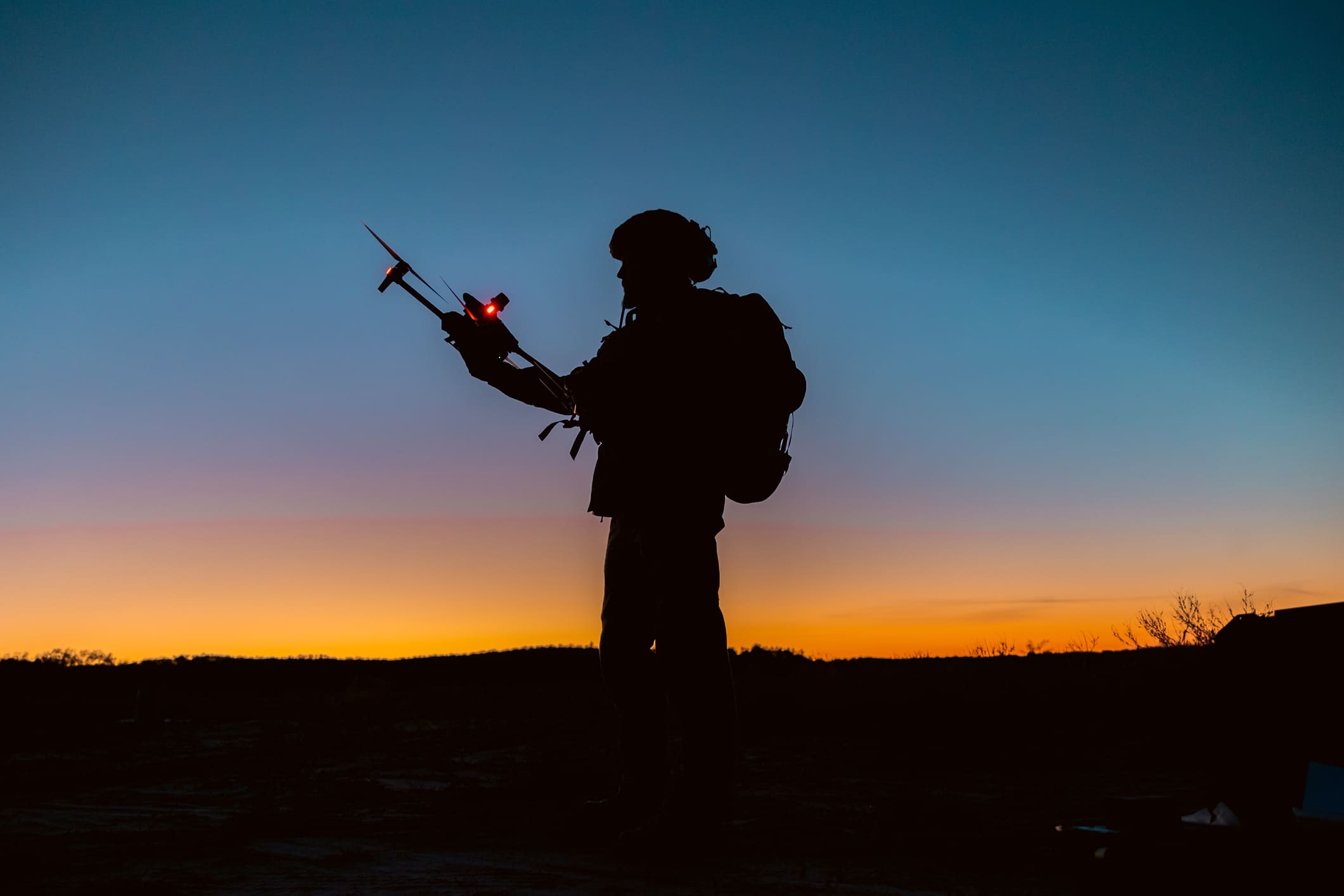 a soldier operating a drone at sunset